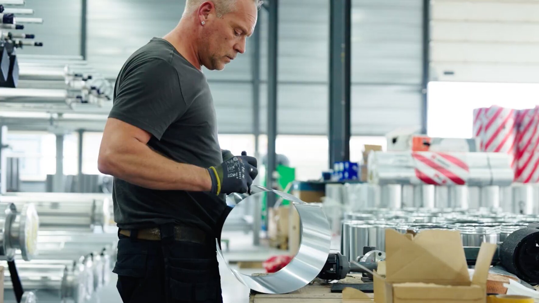 Medewerker vormt een ronde metalen mantel aan de werkbank in de werkplaats