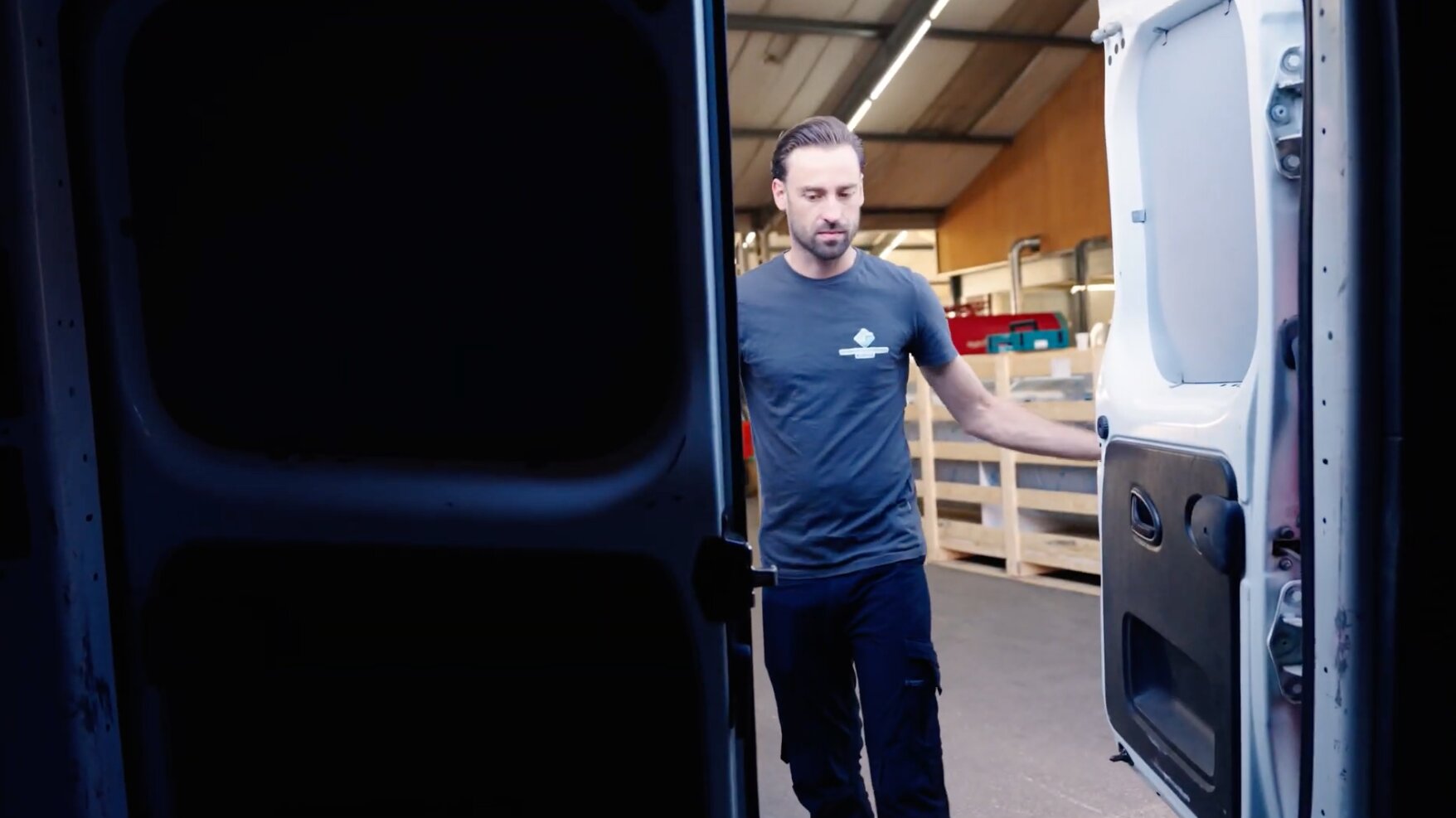 Medewerker opent de achterdeuren van een bedrijfsbus in de werkplaats