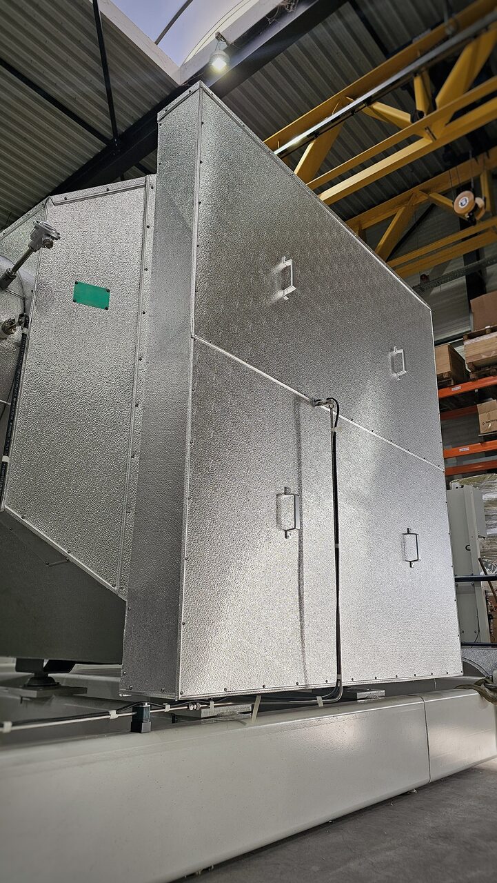 Ommanteling van geribd aluminium plaatwerk met handgrepen op een uitlaatsysteem in een productiehal