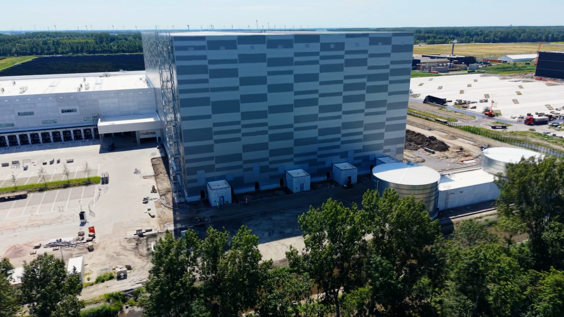 Luchtfoto van een hoogbouwmagazijn met ronde opslagtanks op een nieuw bedrijventerrein