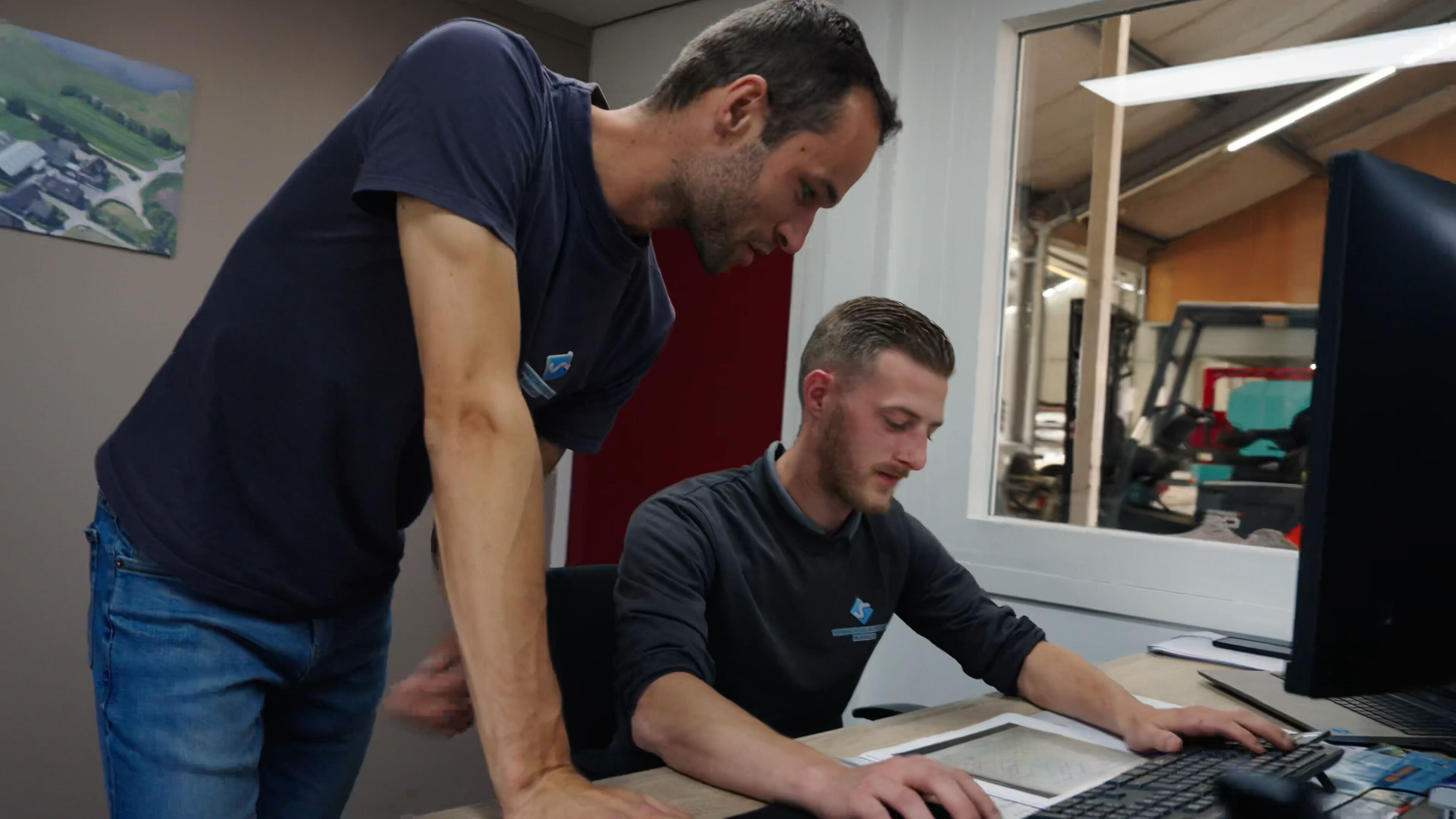 Twee medewerkers bekijken samen een tekening achter de computer op kantoor