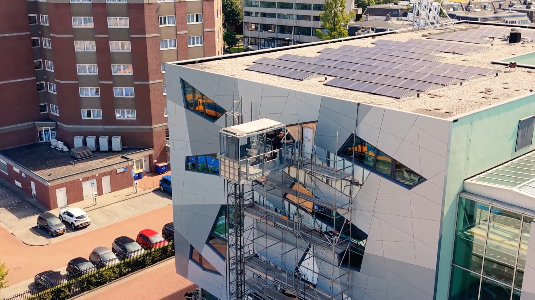 Gebouw met een bouwlift langs de gevel en zonnepanelen op het dak