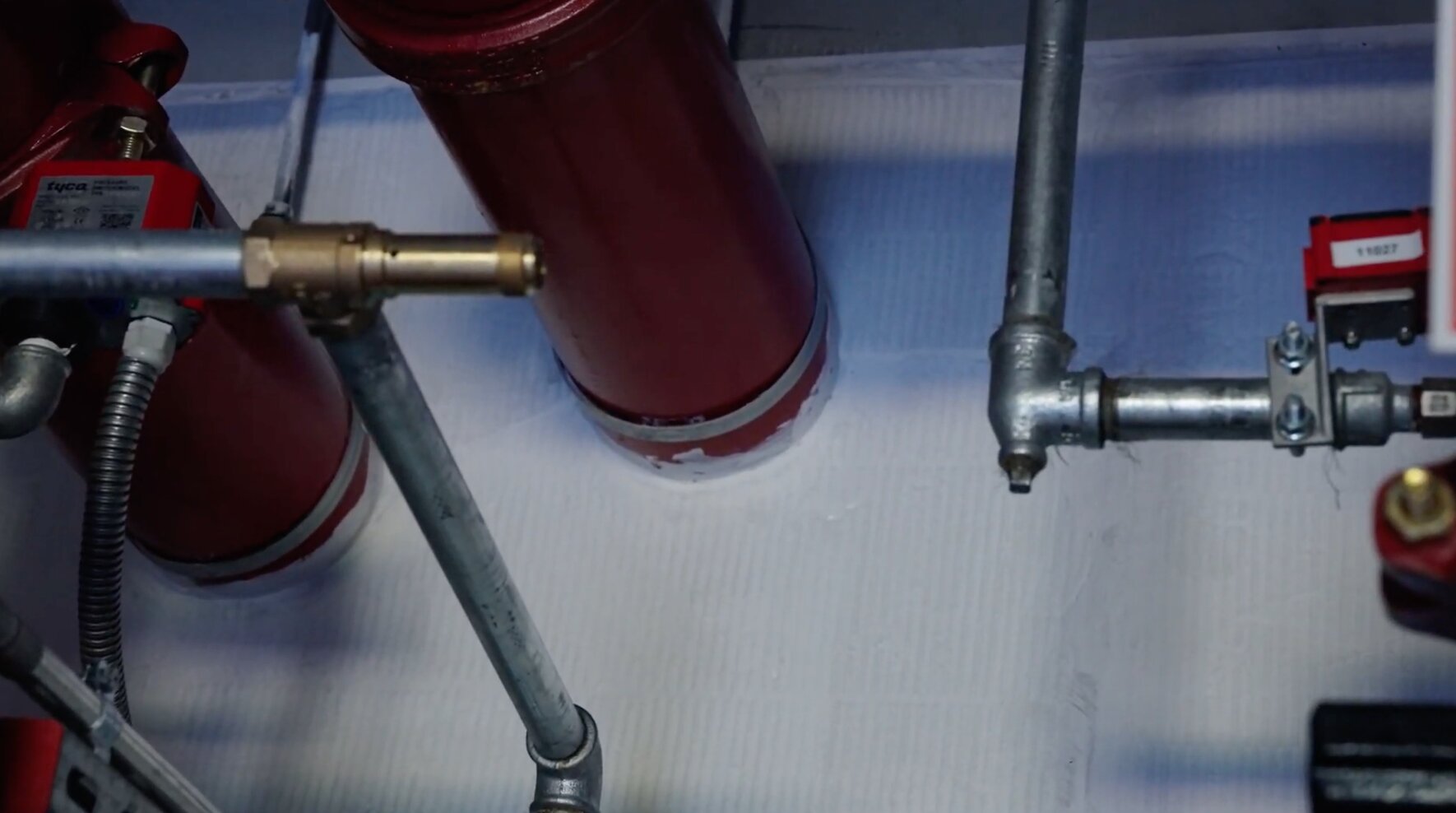 Rode sprinklerleidingen en verzinkte leidingen bij afgedichte doorvoeringen in een wit plafond